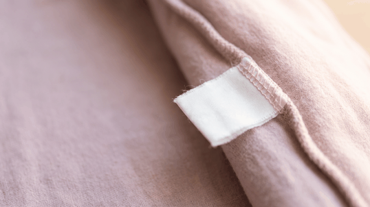 Étiquette cousue dans la couture d'une gigoteuse, là où figure l'indice TOG